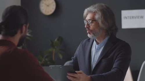 Personalmanager mittleren Alters führt Vorstellungsgespräch mit einem männlichen Kandidaten
