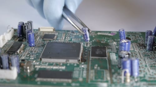 Technician Places Capacitor on Circuit Board