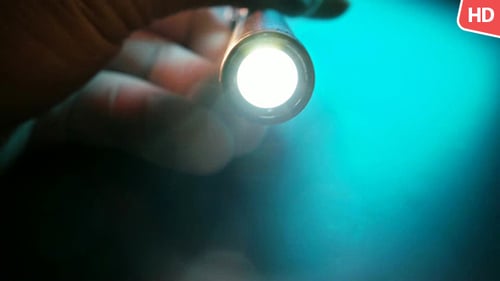 Hand Holding Silver Flashlight Showing Light