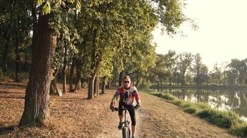 Man Rides a Bike Near Lake