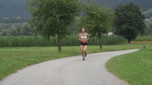 Woman Jogging on Paved Road in Countryside