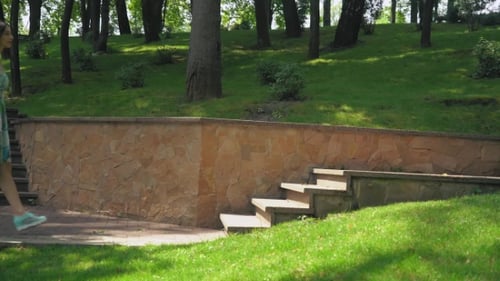 Woman Walking Up Stairs in Park on Sunny Day