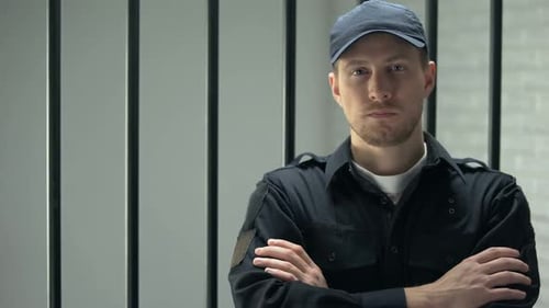 тюремный охранник смотрит в камеру с выражением боли