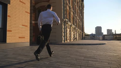 Jovem empresário com maleta correndo pela rua da cidade