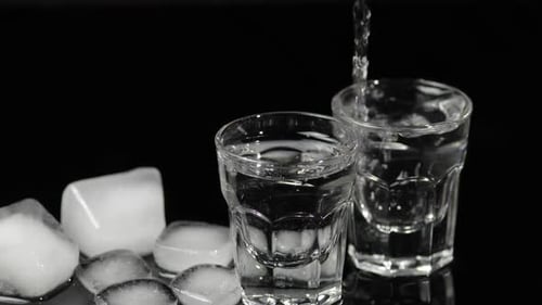 Pouring Clear Liquid Into Shot Glasses with Ice
