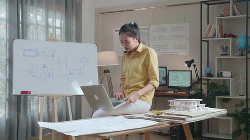 Asian Woman Engineer Sitting On The Table And Using A Laptop To Work At The Office