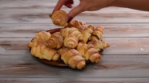 Woman's Hand Lays Homemade Bagels of Cottage Cheese Dough on a Plate in Rustic Style Wooden