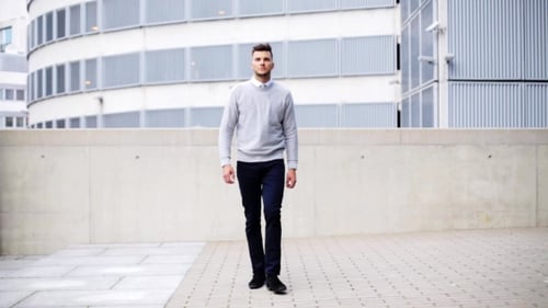 Young Man Walking Along City Street