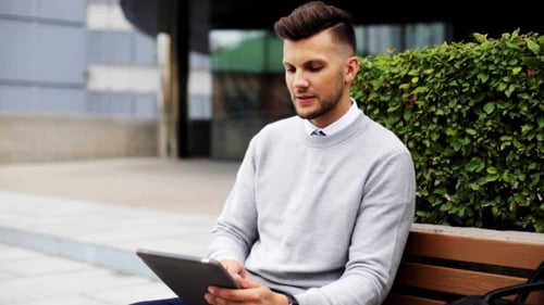 Man With Tablet Pc Sitting On City Street Bench