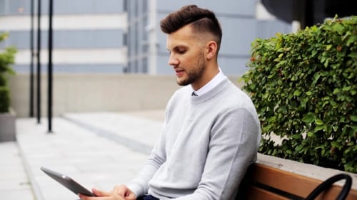 Man With Tablet Pc Sitting On City Street Bench