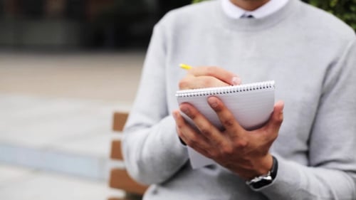 Man With Notebook Or Diary Writing On City Street