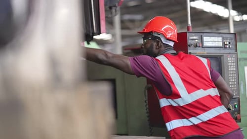 African American male factory worker operating control machinery in construction site