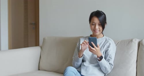 Woman Relaxing on Couch Using Smartphone