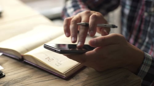 Writing in Notebook Using Mobile Phone Close Up