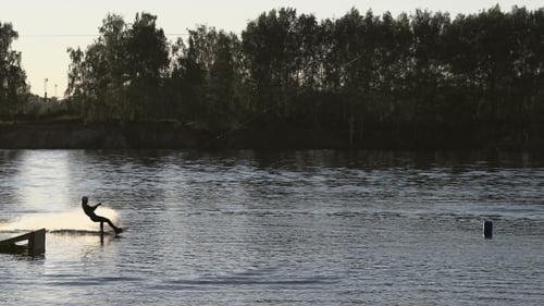 Wakeboarder haciendo trucos en la puesta de sol