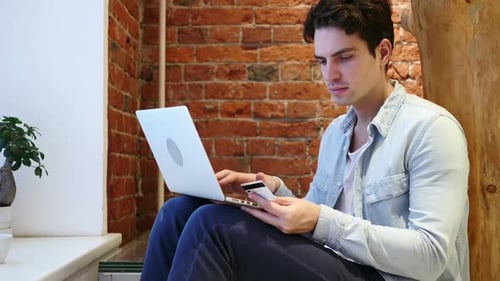 Young Adult Shopping Online with Laptop and Card