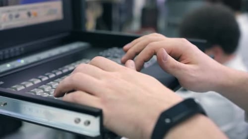 Hands Typing on Server Room Keyboard