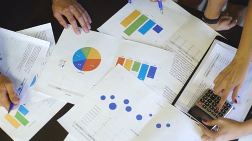 Businessman And Woman Discussing On Stockmarket Charts In Modern Office