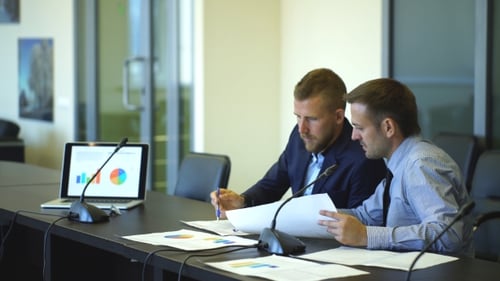 Businessmen Analyze Data Charts in a Workplace