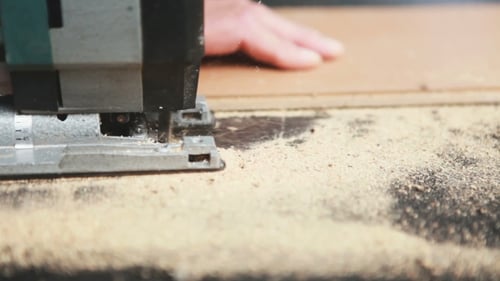 Man Cuts Wood with Jigsaw Tool Close-up