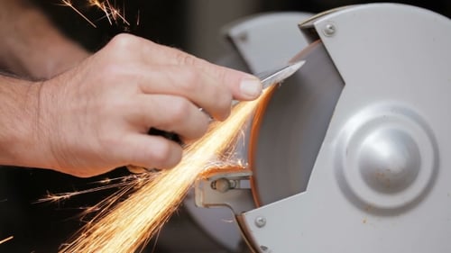 A Man Sharpens a Metal Part Of The Machine