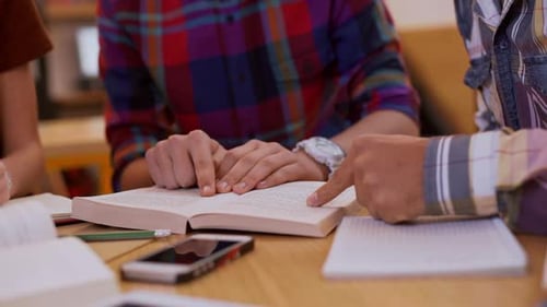 Close Up Footage of Three Friends Sitting at Library Reading Book and Underlining with Pencil in