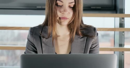 Besorgte Frau arbeitet am Laptop und schaut weg und denkt daran, Probleme im Büro zu lösen
