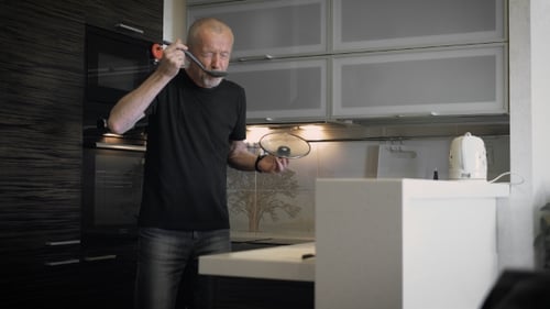 Mature Adult Tasting Soup in Modern Kitchen