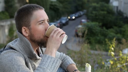 Man Enjoys Food and Drink in Urban Setting