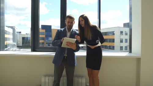 Businesswoman And Businessman Standing In Office And Discuss The Business Plan