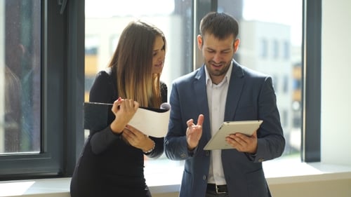Colleagues Discussing Graphs In Office Near Window