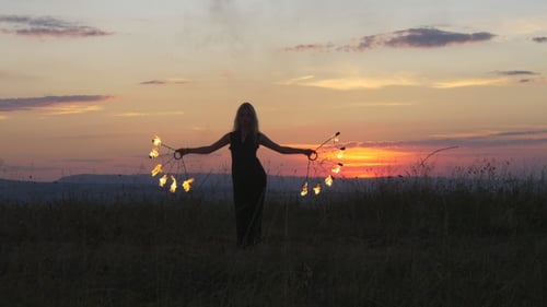 Woman Performs Fire Dance in Rural Field at Sunset