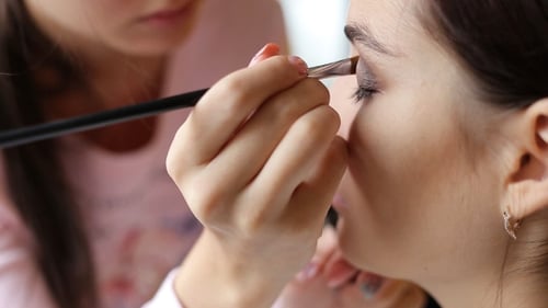 Makeup Artist Applying Eyeshadow to Young Woman