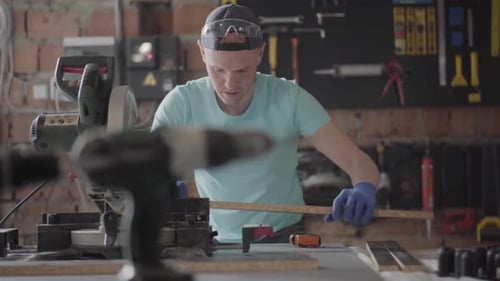 Skilled Carpenter Cutting a Piece of Chipboard Detail in His Woodwork Workshop, Using a Circular Saw