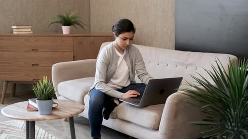 Woman Using Laptop on Couch at Home