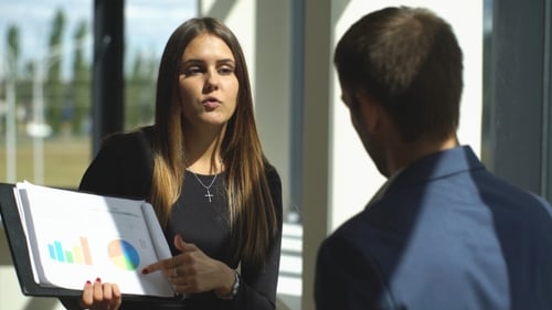 Young Woman Presents Graphs and Charts in Office