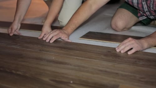 Adults Installing Laminate Flooring in Home