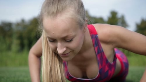 Woman Doing Push-Ups on Grass in Sports Outfit