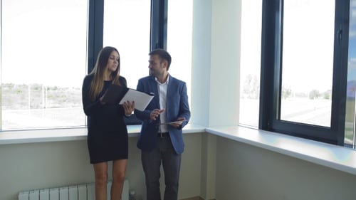 Businesswoman And Businessman Standing In Office And Discussing Business Ideas