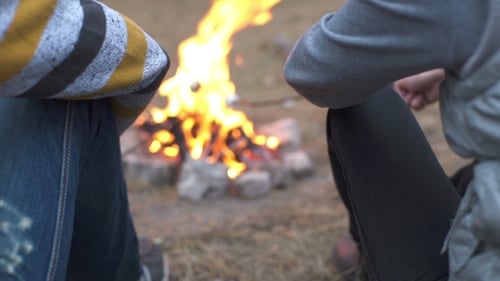 Group Of People Having a Party Outdoors And Cooking Meat On Campfire