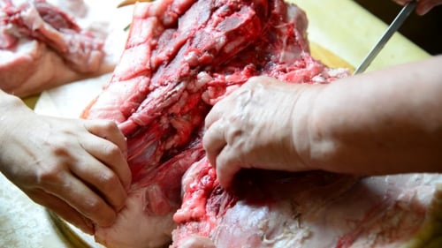 Dos mujeres cortan un pedazo grande de carne de cerdo