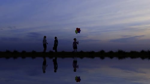 Family Silhouettes with Balloons Reflecting in Serene Water at Sunset