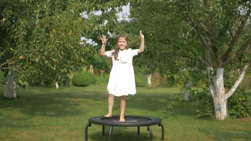 The Little Girl Jumping On The Trampoline In The Park
