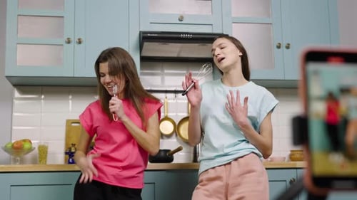 Two Young Women Singing and Dancing in Kitchen