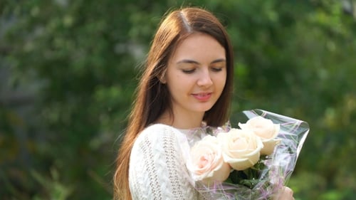 Smiling Woman Smells Bouquet of Pink Roses