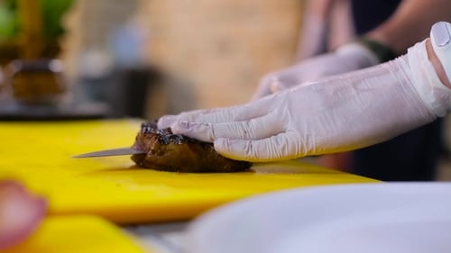 Chef Slices Meat on Yellow Cutting Board