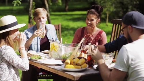 Happy Friends Having Dinner At Summer Garden Party