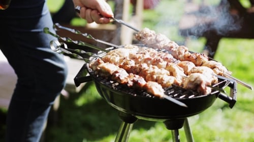 Man Cooking Meat On Barbecue Grill At Summer Party