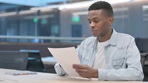 African Man Reading Documents in Office