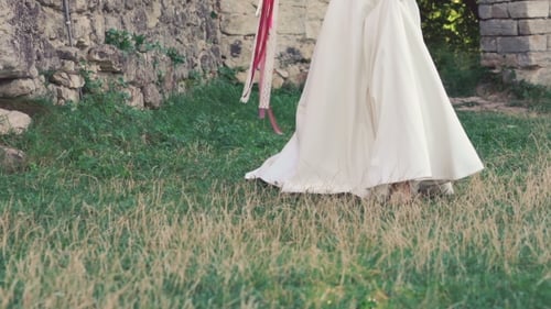 Bride In Wreath Wakling With Bouquet Near The Castle